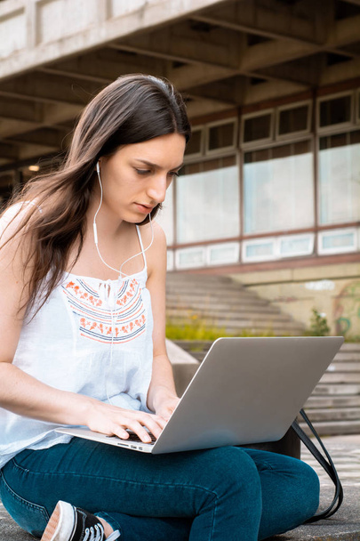 Portrait of young female student using laptop computer outdoors. Education concept - Fotó, kép