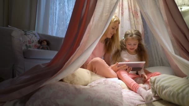 Young mother and her daughter having fun using tablet playing apps - Séquence, vidéo