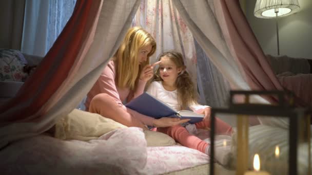Boldog család anya és vele a kis lányom Olvasson egy könyvet a sátor otthon - Felvétel, videó