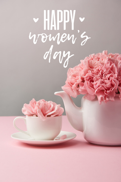 pink carnation flowers in cup and teapot on grey background with happy womens day lettering - Φωτογραφία, εικόνα
