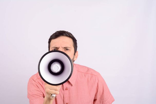 Portrait of young man screaming on a megaphone. Marketing or sales concept. - Foto, afbeelding