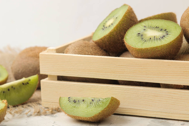 Délicieux beaucoup de kiwi fruits mûrs et kiwi coupés dans un tiroir sur un fond de béton léger. gros plan
 - Photo, image