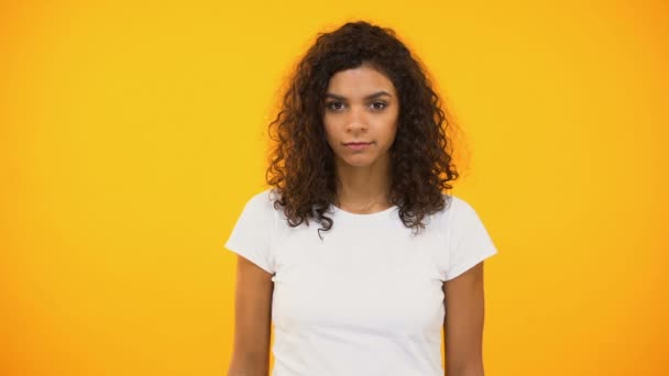 Serious biracial woman showing no gesture to camera against yellow background - Metraje, vídeo