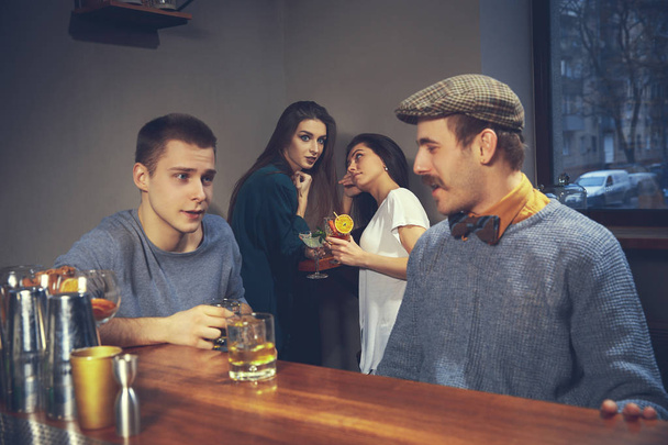 Two young men in casual clothes sitting at bar counter in pub - 写真・画像
