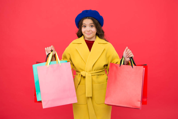 Obsessed with shopping. Girl cute kid hold shopping bags red background. Get discount shopping on birthday holiday. Fashionista adore shopping. Customer satisfaction. Prime time buy spring clothing - Fotó, kép