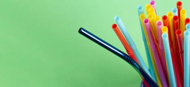 Stainless steel reusable drinking straw with plastic straws on green background - Photo, Image