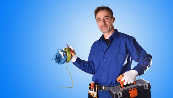 Background with uniformed electrician with tools and electrical equipment and blue background. Front view. Half body - Фото, зображення