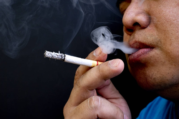 Hombre fumando un cigarrillo, Imagen de cigarrillo en la mano con humo
 - Foto, imagen
