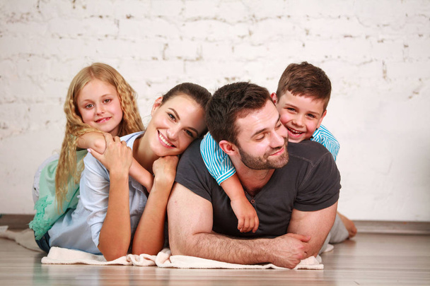Happy dreamy young couple of parents with two children at home having fun together - Photo, Image