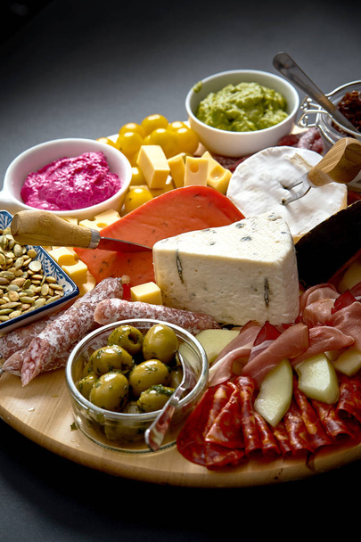 Antipasti fedélzet-val különböző sajt és a hús ételek hummus és olajbogyó, fából készült táblán - Fotó, kép