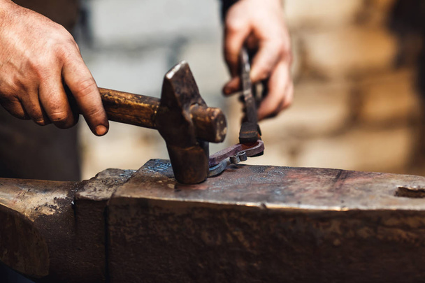 blacksmith makes an artistic forging of hot metal on the anvil. - Foto, imagen