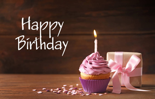 Delicious cupcake with candle and gift box against wooden background. Happy Birthday - Photo, image