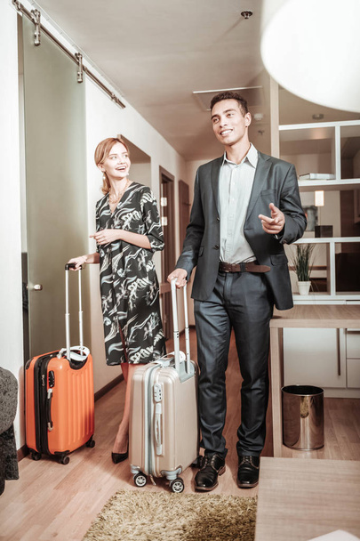 Husband and wife caring their luggage while entering hotel room - Valokuva, kuva