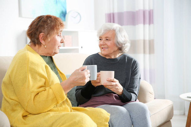 Elderly women drinking tea together in living room - Foto, Imagen