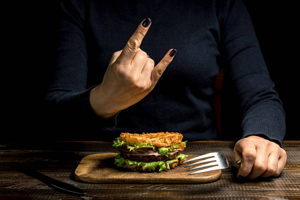 Υγιεινού τρόπου ζωής, η σωστή διατροφή. Γυναικεία χέρια δείχνουν «ήρεμα» πάνω από ένα burger υγιή ρύζι με λαχανικά, μυρωδικά και κοτολέτα σε ένα ξύλινο ταμπλό. Οριζόντιο πλαίσιο - Φωτογραφία, εικόνα