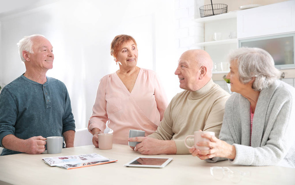 Elderly people spending time together at table in kitchen - Photo, image