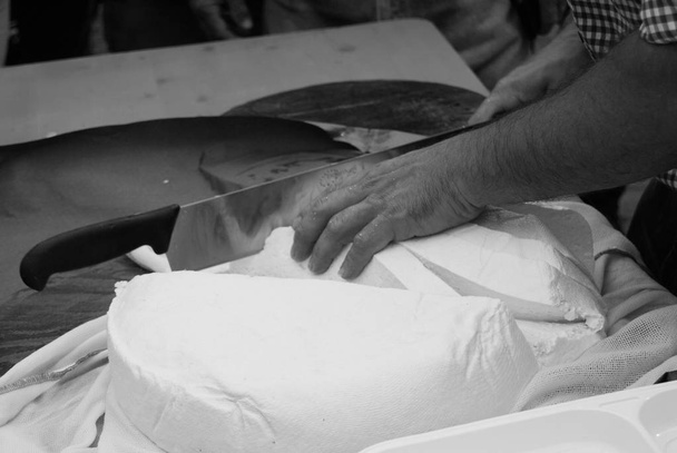 Kaasproducent een verse kaas met speciale mes snijden - Foto, afbeelding