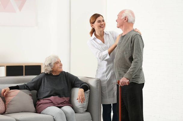 Elderly spouses with female caregiver in living room - Fotoğraf, Görsel