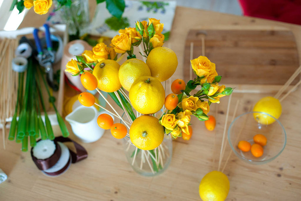 Floristics hobby. Floral and fruits bouquet making process. Overhead still life of bouquet making process - 写真・画像