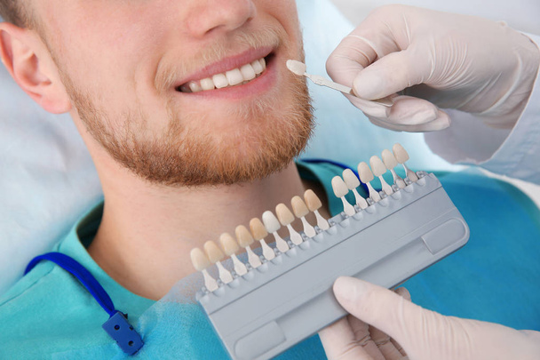 Dentist selecting patient's teeth color with palette in clinic, closeup - Фото, зображення