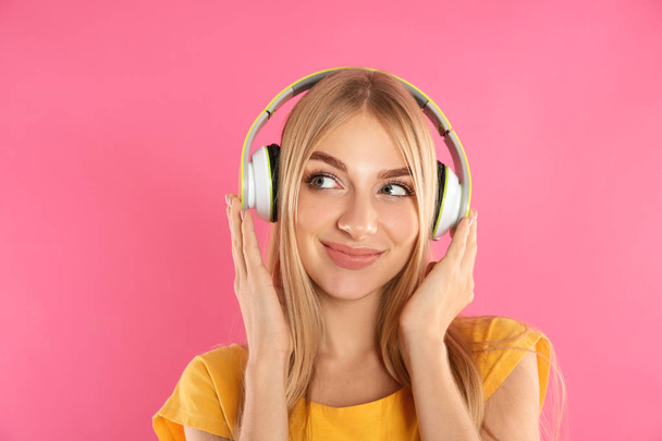 Beautiful young woman listening to music with headphones on color background - Valokuva, kuva