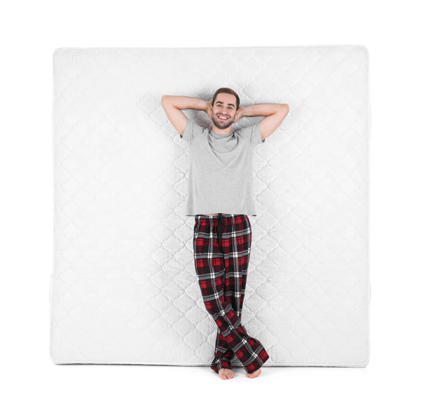 Young man with comfortable mattress isolated on white - Valokuva, kuva