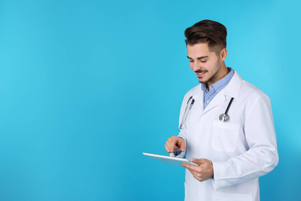 Young medical student with tablet on color background. Space for text - Photo, image