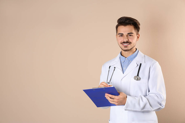 Young medical student with clipboard on color background. Space for text - Foto, imagen