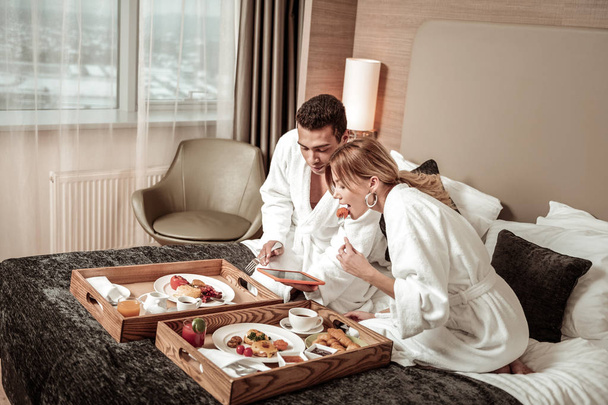 Couple eating breakfast in bed and watching movie on tablet - Foto, immagini