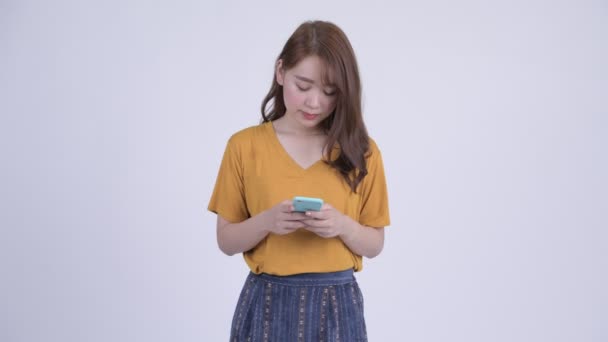 Happy young beautiful Asian woman using phone - Felvétel, videó