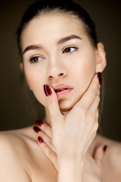 Portrait of young charming girl with natural makeup holding her hands on her face - Foto, Imagem