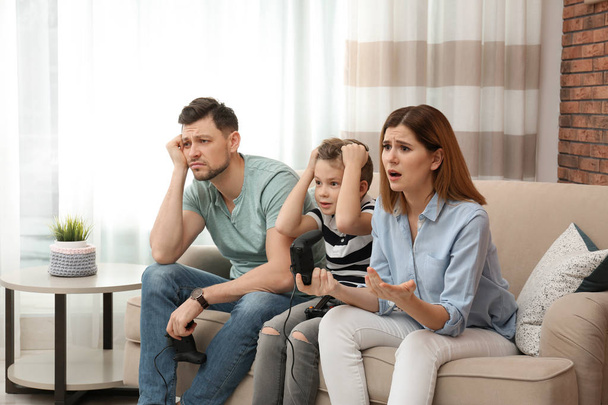 Family playing video games on sofa in living room - Foto, immagini