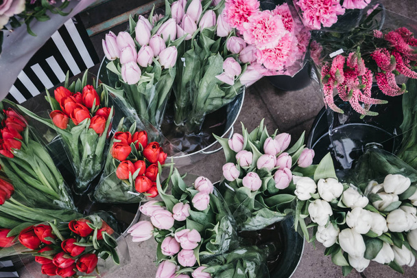 Manojos de tulipanes rojos, rosados y blancos frescos a la venta en un mercado callejero
. - Foto, Imagen