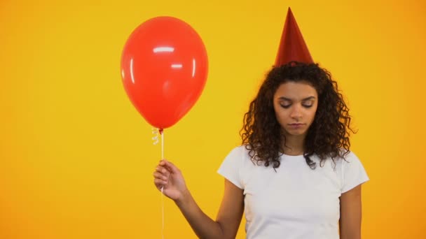 Sad young girl holding red balloon, upset and lonely on birthday celebration - Záběry, video