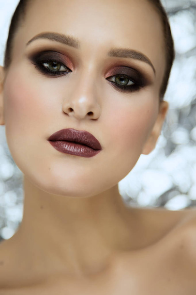 Beauty portrait of young attractive girl wearing makeup in studio on shiny metallic background - Valokuva, kuva