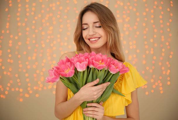 Portrait of smiling young girl with beautiful tulips on blurred background. International Women's Day - Fotografie, Obrázek