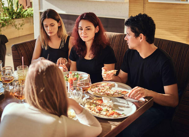 Hora de la pizza. Jóvenes amigos disfrutando de pizza y ensalada en un café al aire libre
 - Foto, Imagen