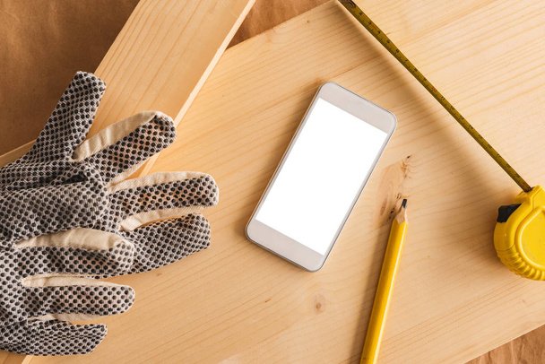 Modern white smartphone with blank screen mock up in small business woodwork carpentry workshop, top view - Photo, Image