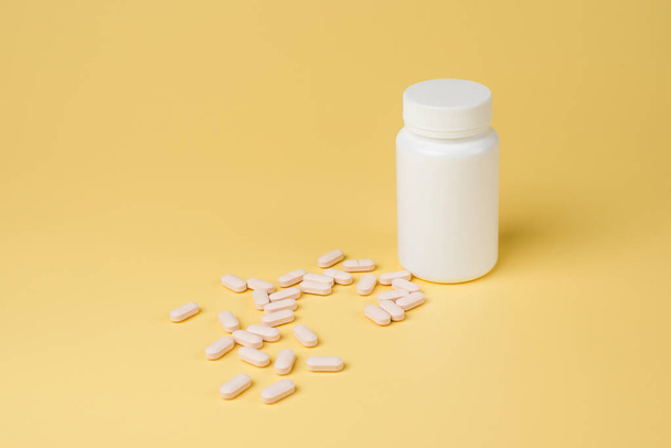 rosa Pillen, Tabletten und weiße Flasche auf gelbem Hintergrund. Kopierraum für Text - Foto, Bild