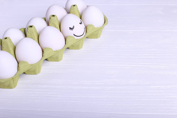 One egg in tray is different smile, copy space. Happy Easter concept greeting card design. - Foto, Imagen