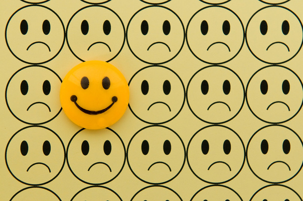 gelber Smiley gegen trauriges Emoticon - Foto, Bild