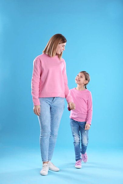 glückliche Frau und Tochter in stilvoller Kleidung auf farbigem Hintergrund - Foto, Bild