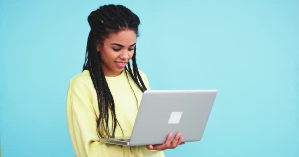 Lovely african woman with dreadlocks work on her notebook she holding on her hands and looking very concentrated , in a studio with a blue background wall - Video