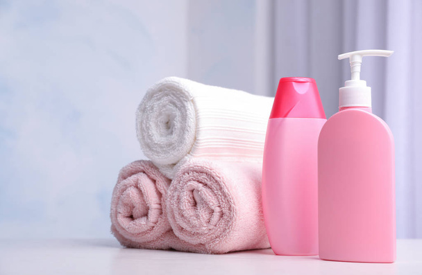 Bottles of shampoo and rolled bath towels on table, space for text - Photo, Image