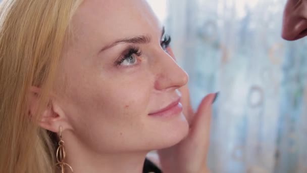 Makeup artist preparing the face of a beautiful woman before applying makeup. - Metraje, vídeo
