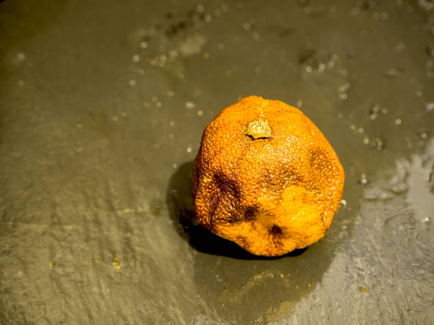 Mandarina podrida ob piedra negra
 - Foto, imagen
