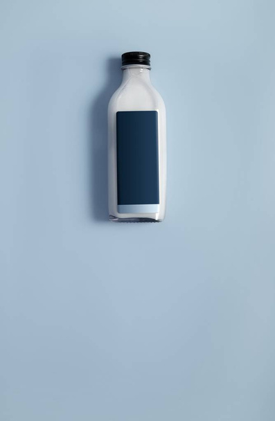 Glass bottle with white liquid (milk, cream, sauce) isolated on colour background - Photo, Image