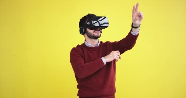 Good looking guy using a VR happy he touching virtual the program to select what he wants , he are very excited in the studio with a yellow background wall. - Video