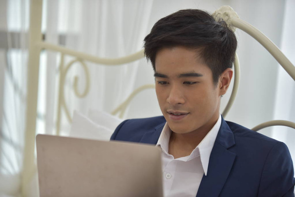 Ázsiai férfi használ laptop az ágyban - Fotó, kép