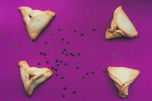 Hamantaschenin keksejä violetin taustan päällä. Yläkuva
 - Valokuva, kuva